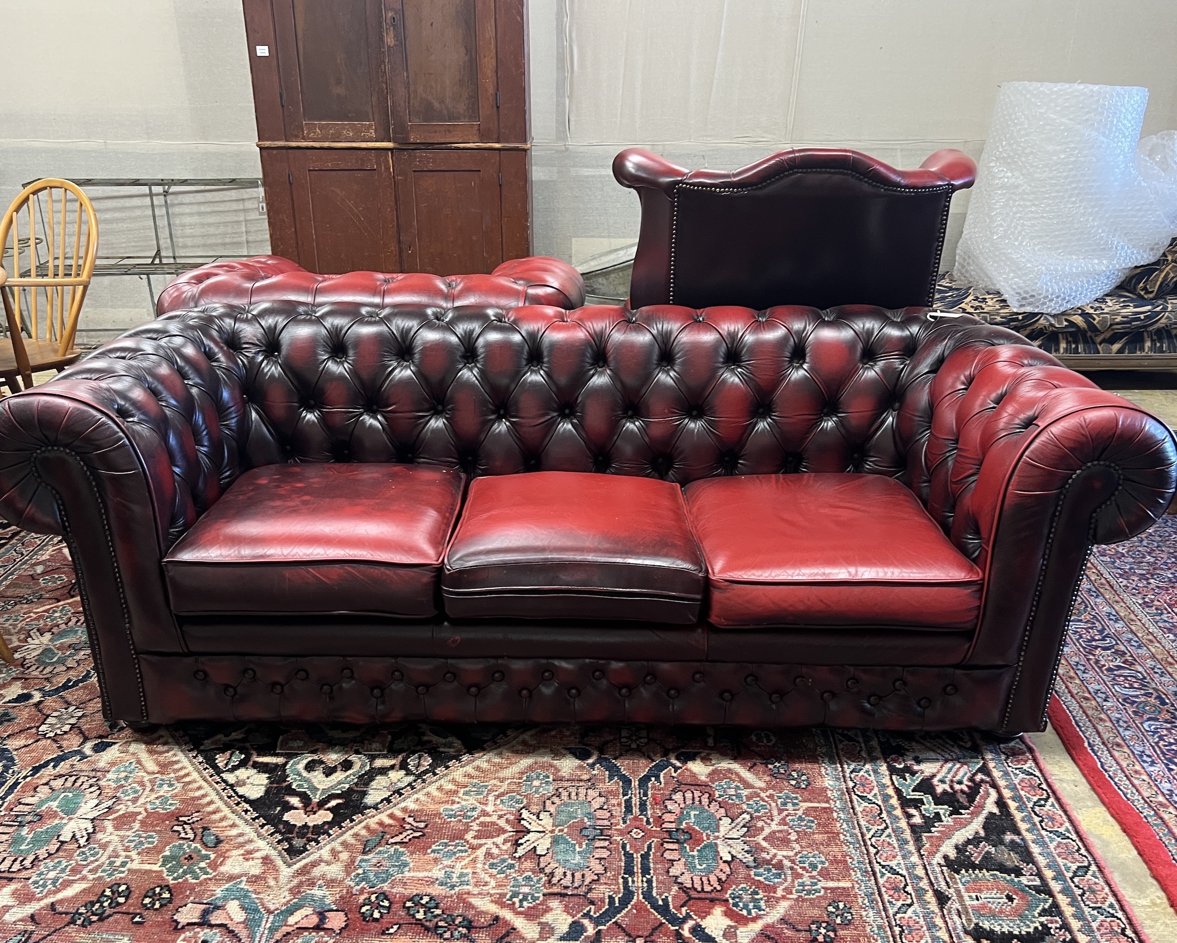 A Thomas Lloyd buttoned burgundy leather Chesterfield sofa, length 200cm, depth 85cm, height 72cm, two leather armchairs and a footstool